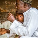 A Muslim Maninke man holds his child in Guinea-Bissau.
