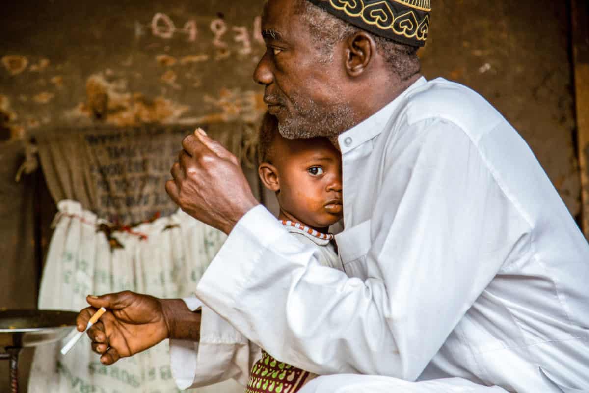 A muslim maninke man holds his child in guinea bissau.